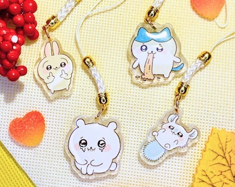 Puede incluir: Cuatro colgantes de acrílico transparente con diseños de animales de dibujos animados, incluyendo un conejo, un gato, un oso y un ratón. Cada colgante está unido a un cordón blanco con detalles metálicos dorados. El fondo incluye bayas rojas y caramelos en forma de corazón.