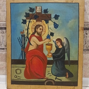 May include: A religious icon depicting a central figure in a red robe offering grapes to an angel holding a golden chalice. A cross, clock, and rooster are also visible. The background is blue with a gold border.