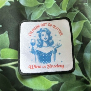 May include: A white patch with black trim features a retro illustration of a woman holding a glass of wine. The text reads "I'm made out of glitter, wine and anxiety".