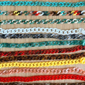 May include: A collection of colorful acrylic chain links in various shades, including turquoise, red, yellow, and brown. The chains are arranged in parallel rows, showcasing a variety of colors and patterns. The chains are suitable for jewelry making or crafting.