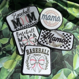 May include: A collection of baseball-themed patches with text like "Baseball Mom" and "Baseball Mama." The patches feature baseballs, bows, and checkered patterns. The color scheme includes black, white, and red accents.