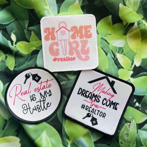 May include: Three white fabric patches with black and pink text and images. The first patch is square and says "Home Girl #realtor" with a pink house and key. The second patch is round and says "Real estate is my hustle". The third patch is square and says "Making dreams come true #realtor" with a black house and key.