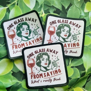 May include: Three white iron-on patches with black borders. Each patch features a retro-style illustration of a woman with red lipstick and a cigarette, holding a glass of wine. The text on the patches reads "One glass away from saying..." with different phrases below. The first patch says "What", the second says "What I really think", and the third says "My think".