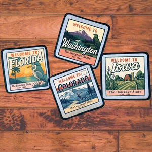 May include: Four square patches with state-themed designs. The patches read "Welcome to Florida," "Welcome to Washington," "Welcome to Iowa," and "Welcome to Colorado." Each patch features state-specific imagery and text, set against a light blue background.
