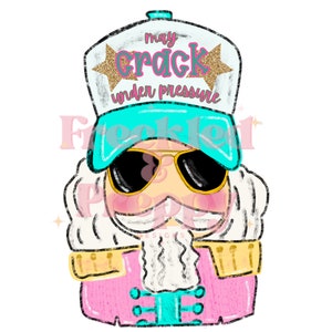 May include: A cartoon illustration of a nutcracker wearing sunglasses and a hat with the text "may crack under pressure." The nutcracker has a pink coat, a white beard, and gold accents. The hat is white with a teal brim and the text "may crack under pressure."