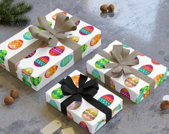 Pode incluir: Três caixas de presente embrulhadas em papel branco com um padrão de ovos de Páscoa coloridos. As caixas são amarradas com laços de fita marrom e preto.