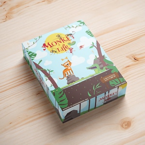 May include: A colorful board game box with a jungle theme. The box features a cartoon tiger, a crocodile, and monkeys. The game is called "Monkey Life" and is for 1 to 4 players, ages 7 and up.