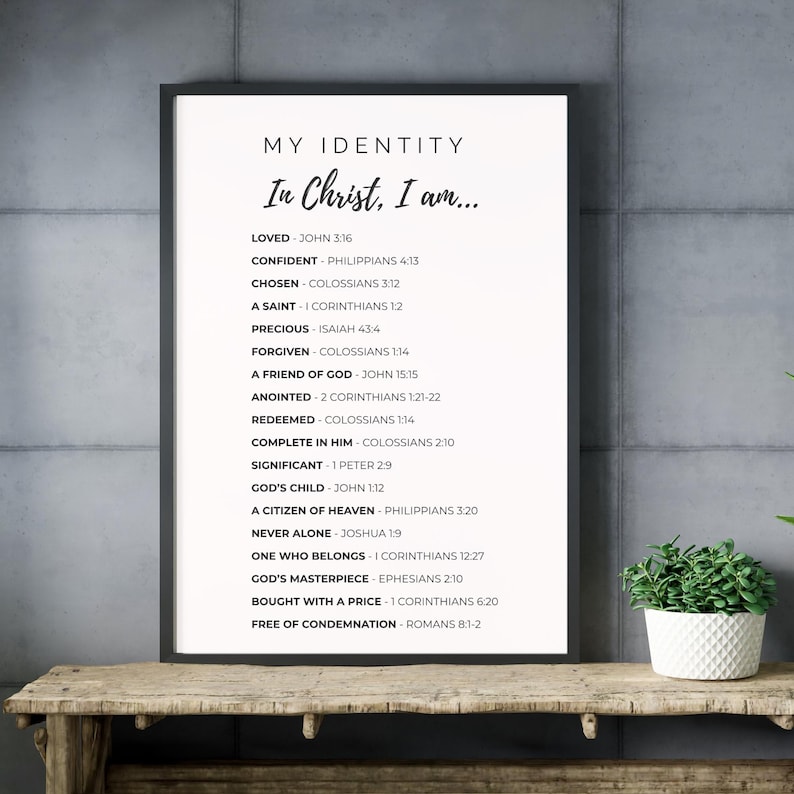 May include: A framed print with the text "MY IDENTITY In Christ, I am..." followed by a list of affirmations and corresponding Bible verses. The print is in black and white and is displayed on a wooden surface.
