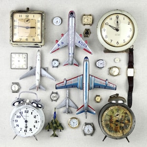 May include: A collection of vintage items including several analog alarm clocks, wristwatches, and die-cast model airplanes. The assortment features a large square clock, a round Westclox Big Ben clock, and various metal aircraft with airline markings.