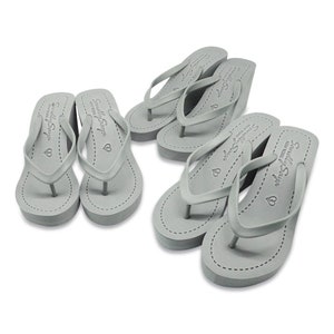 May include: Four pairs of gray wedge flip flops with the text "Simply Soya" and a heart symbol on the strap.
