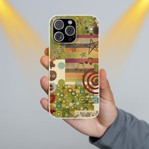 May include: A phone case with a colorful collage design. The case features a mix of patterns, including circles, stripes, and musical notes, with a star and the text "Post Card e-fruit". The case is held in a person's hand.