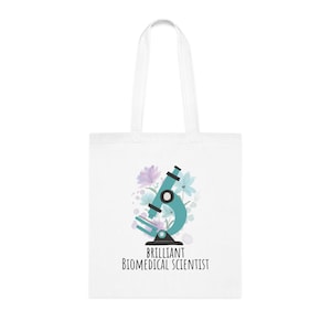 Può includere: Borsa tote bianca con un design di microscopio turchese e accenti floreali viola e blu. Il testo "BRILLIANT BIOMEDICAL SCIENTIST" è stampato sotto. La borsa ha due manici bianchi.