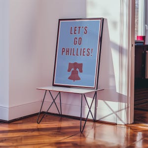 Philadelphia Phillies Baseball Poster in the team's retro or vintage throwback uniform colors maroon red and baby powder blue. States Lets Go Phillies in the maroon red color and the background of the poster is the light blue. A great poster gift for Phillies fans and for kids or children's rooms who want a Philadelphia themed bedroom or game room. Poster comes in a variety of sizes from small sizes to large poster sizes.