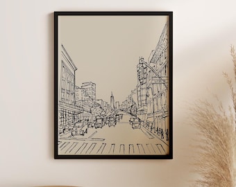 May include: Black and white line drawing of a city street scene with buildings, cars, and pedestrians. The drawing is on a beige background and framed in a black frame.