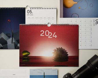 Peut inclure: Un calendrier rouge avec l'année 2024 imprimée en blanc. Le calendrier a une photo d'un coucher de soleil sur une étendue d'eau rouge avec une feuille verte et une fleur violette flottant à la surface.