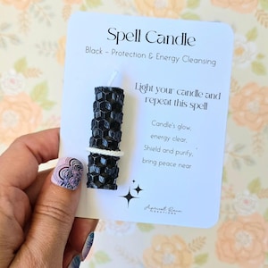 May include: Black spell candle with a white label that reads "Spell Candle" and "Black - Protection & Energy Cleansing". The label also includes instructions to light the candle and repeat the spell: "Candle's glow, energy clear, Shield and purify, bring peace near".