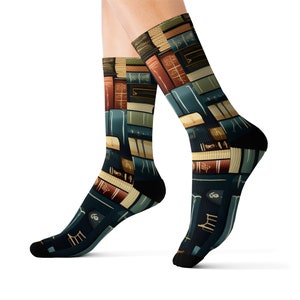 May include: Knee-high socks with a repeating pattern of books in various colours. The socks have a dark blue background with black heels and toes. The books are in shades of brown, green, and blue.