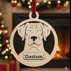 May include: A wooden Christmas ornament featuring a dog's face. The dog's head is in a circular frame with a red ribbon for hanging. The word "Custom" is engraved on a dog tag shape below the dog's face. The background is blurred.