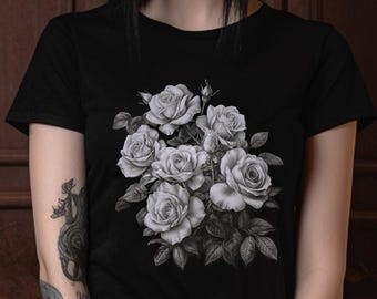 May include: A black short-sleeved t-shirt featuring a detailed, monochromatic graphic print of a cluster of blooming roses with leaves centred on the chest. The shirt has a crew neckline and a standard fit, showcasing a floral botanical illustration.