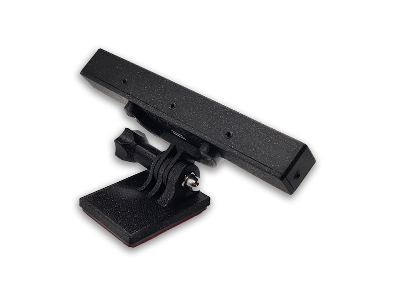 May include: Black camera mount with an adhesive base and a GoPro mount. The mount is designed to be attached to a flat surface.