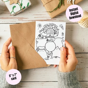 May include: A 5" x 7" black and white card with the text "Merry Christmas! You're the reason I Love Coming to SCHOOL!" is held in a brown envelope. The card has a snowman and other holiday-themed illustrations.