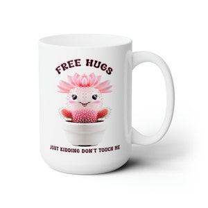 May include: White ceramic mug with a pink cactus illustration and the text "FREE HUGS JUST KIDDING DON'T TOUCH ME".