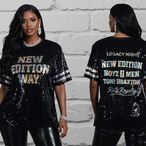 May include: Black sequined t-shirt with the text "NEW EDITION WAY" on the front. The back of the shirt features the text "LEGACY NIGHT" and the names "NEW EDITION, BOYZ II MEN, TONI BRAXTON, R&B Royalty". The shirt has silver stripes on the sleeves.