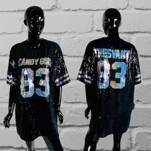 May include: Black sequined jersey-style shirt with the text "CANDY GIRL" and the number "83" in iridescent sequins on the front. The sleeves have white stripes. The back of the shirt has the text "TRESVANT" and the number "83".