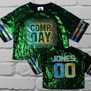 Comp Day Bling Sequin Top, Comp Day text in a scattered spangle bling holographic design on the front, Cutom bling name and number on the back, custom bling jersey sleeve stripes on a green full sequin top, Custom bling, Custom Sequin Shirt, Football Bling, Cheer Bling, Birthday Bling, scattered spangle bling holographic design on the front, Custom bling, Custom Sequin Shirt, Football Bling, Cheer Bling, Birthday Bling, Sports Bling, Custom Name and Number