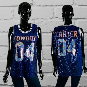May include: A sequined blue tank top with white trim and the word "COWBOY" and the number "04" on the front. The back of the tank top has the name "CARTER" and the number "04". The tank top is displayed on a black mannequin.