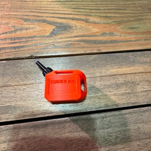 May include: A small, bright orange plastic gasoline can with a black spout and the word "GASOLINE" printed on the side.