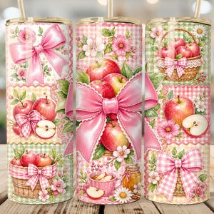 Könnte beinhalten: Drei zylindrische Becher mit Strohhalmen, die ein wiederkehrendes Muster aus roten Äpfeln, rosa Vichy-Stoff, großen rosa Schleifen und geflochtenen Körben zeigen. Das Design umfasst Blumenakzente, Apfelscheiben und Honiggläser auf einem Pastellhintergrund.