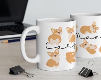 May include: Two white ceramic mugs with a black and white design of corgis in various poses. The text "Mama Corgi" is printed on the mugs.