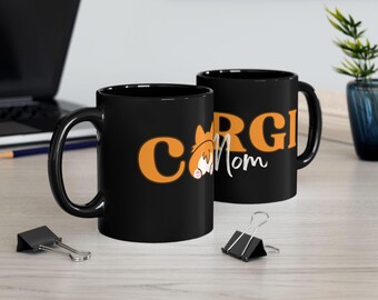 May include: Two black ceramic mugs with a white and orange design. The mugs say "Corgi Mom" with a cartoon corgi on the left mug.