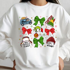 May include: White sweatshirt with a festive holiday design. The design includes images of a van, bows, and characters with text that reads "The Wet Bandits", "Santa's Helper", "You Serious Clark?", and "Oh Fudge!"