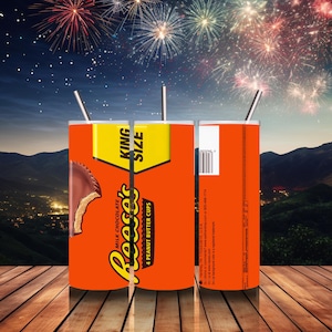 May include: A cylindrical tumbler featuring a vibrant orange design with the Reese's logo and "KING SIZE" text. The tumbler showcases a graphic of a Reese's Peanut Butter Cup. Includes a silver straw. The background features fireworks.