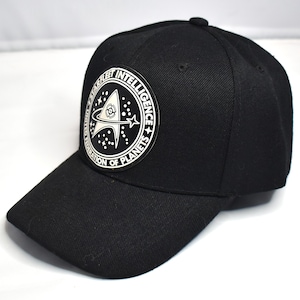 Op de afbeelding: Zwarte baseballcap met een witte patch met het Starfleet Intelligence logo. Het logo bevat een ster, planeet en de tekst "Starfleet Intelligence, United Federation of Planets". De cap heeft een gebogen klep en een knoop aan de bovenkant.