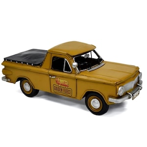May include: A yellow vintage toy pickup truck with a black canvas bed cover. The truck has a "Golden Fleece" logo with a sheep on the side.