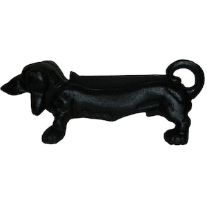 May include: Black cast iron dachshund fireplace log holder. The dachshund is in a lying down position with its tail curled up.