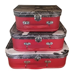 May include: Three red and black vintage-style suitcases with a black and white patterned design. The suitcases are stacked on top of each other, with the largest suitcase on the bottom and the smallest suitcase on top.