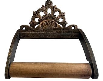 May include: A cast iron toilet roll holder with a decorative scrollwork design and the letters "GWR" in the centre. The holder has a wooden dowel for the paper roll.
