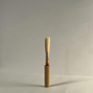 May include: A wooden clarinet reed with a silver band and a brown wooden barrel.
