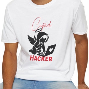 Può includere: Maglietta bianca con una grafica nera e rossa di un angelo cupido che hackerà su un laptop. Il testo "Cupid Hacker" è stampato sotto la grafica.