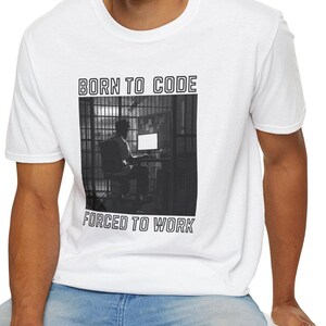 May include: White t-shirt with a black and white graphic of a person sitting at a computer in front of a window with bars. The text "Born to Code" and "Forced to Work" is printed on the shirt.