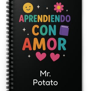 May include: Black spiral notebook with the text "Aprendiendo con amor" in rainbow colors. The notebook also has a smiley face, a flower, a book, and two hearts. The name "Mr. Potato" is printed at the bottom.