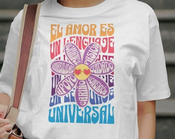 May include: White t-shirt featuring a colourful flower graphic and the text "El amor es un lenguaje universal".