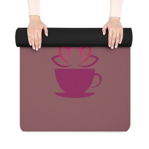 May include: A purple yoga mat with a stylized pink lotus flower and a purple coffee cup design.