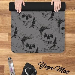 May include: Gray yoga mat with a skull pattern and the text "True Storyboard" printed on the bottom. The mat is rolled up and held by two hands.