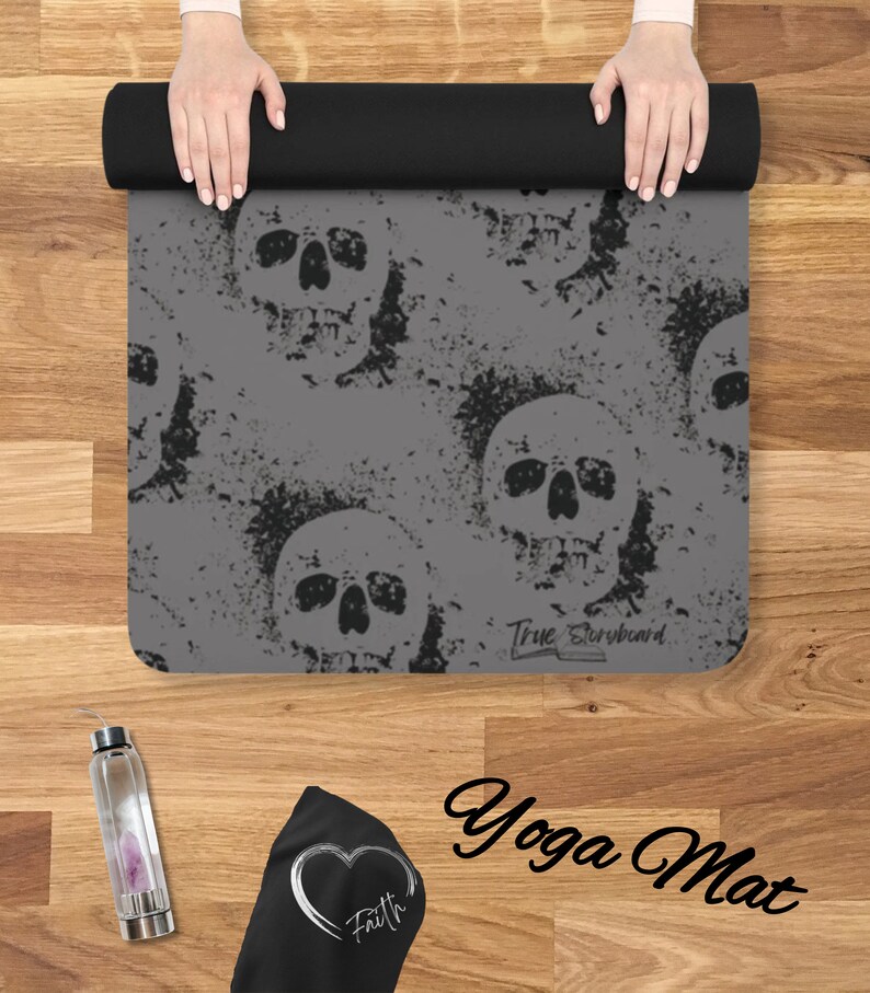 May include: Gray yoga mat with a skull pattern and the text "True Storyboard" printed on the bottom. The mat is rolled up and held by two hands.