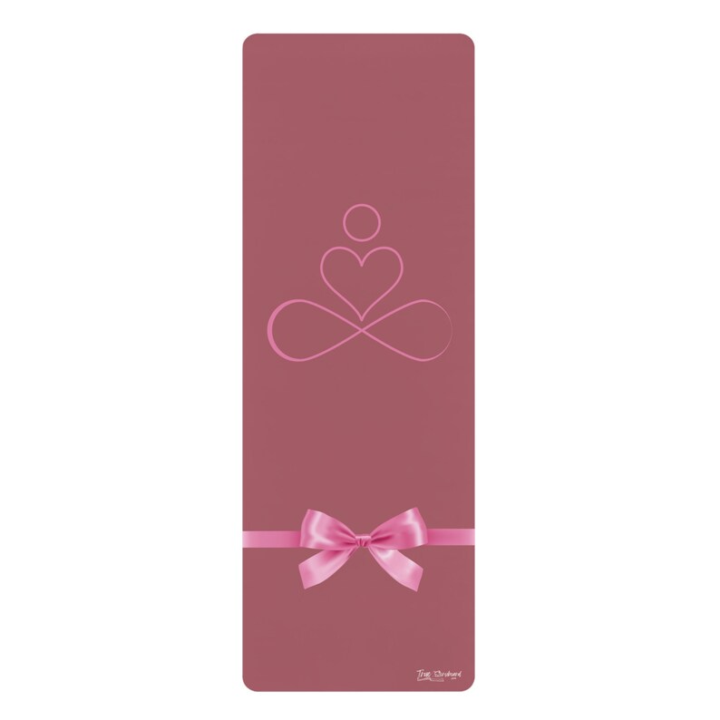 May include: A pink yoga mat with a pink infinity symbol and heart design. The mat has a pink bow on it and the text "The Orchard" at the bottom.